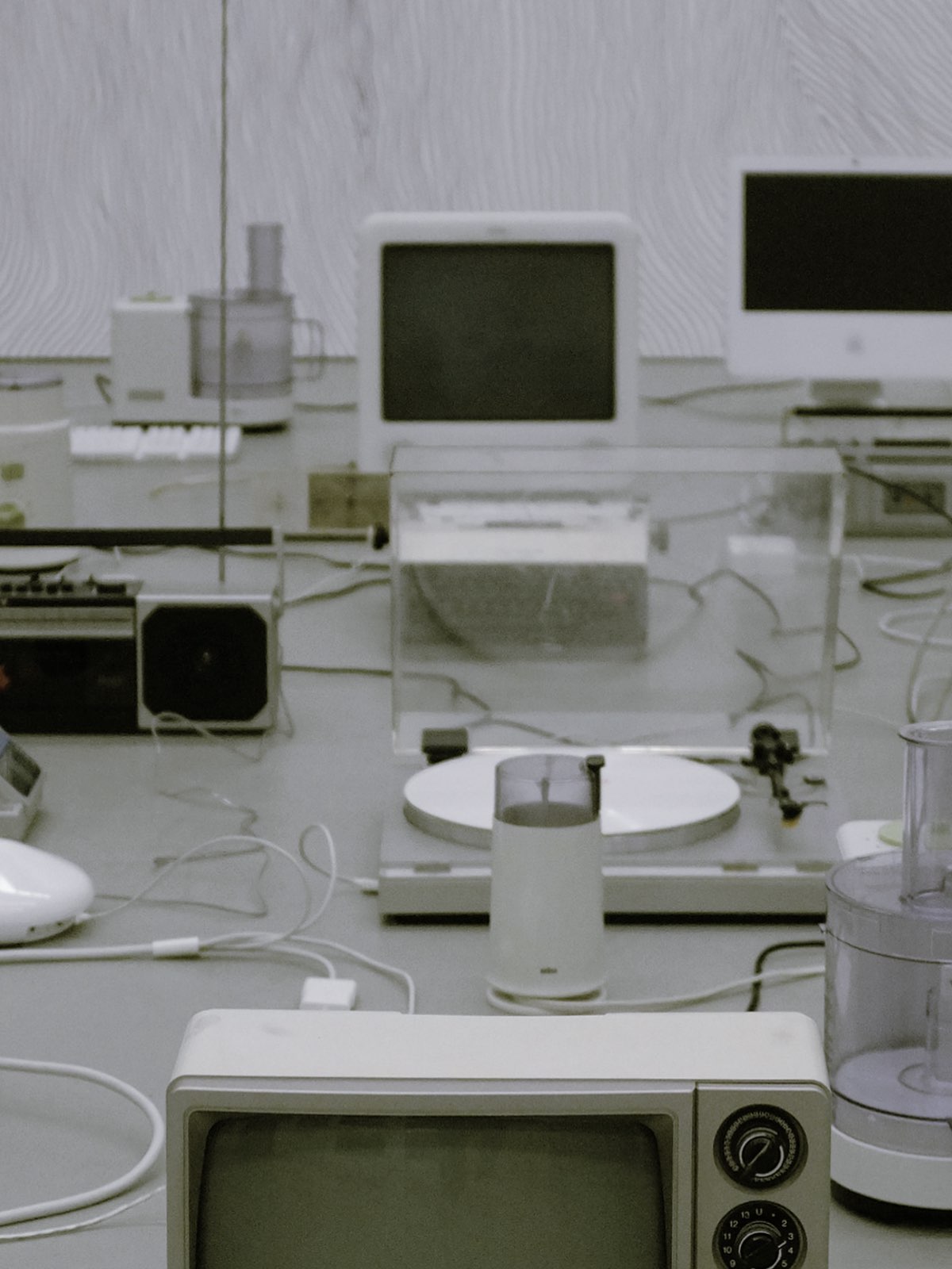 Shallow focus cropped photo of a sprawling installation of older mostly plastic electronics. Cables run between them indiscriminately.